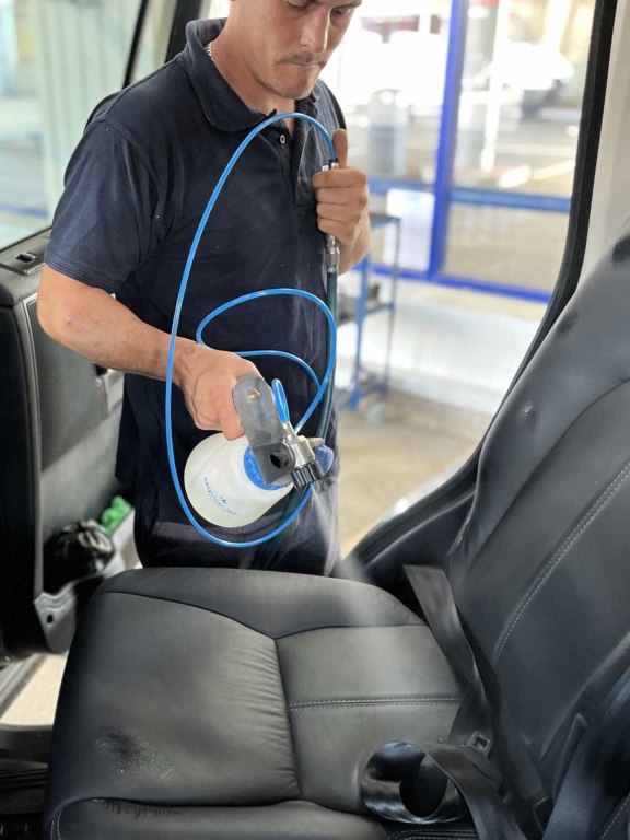 James spraying antimicrobial treatment over a car interior, including leather seats