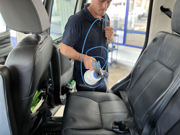 James applying antimicrobial decontamination spray to leather car seats during an interior car detailing service in Chelmsford